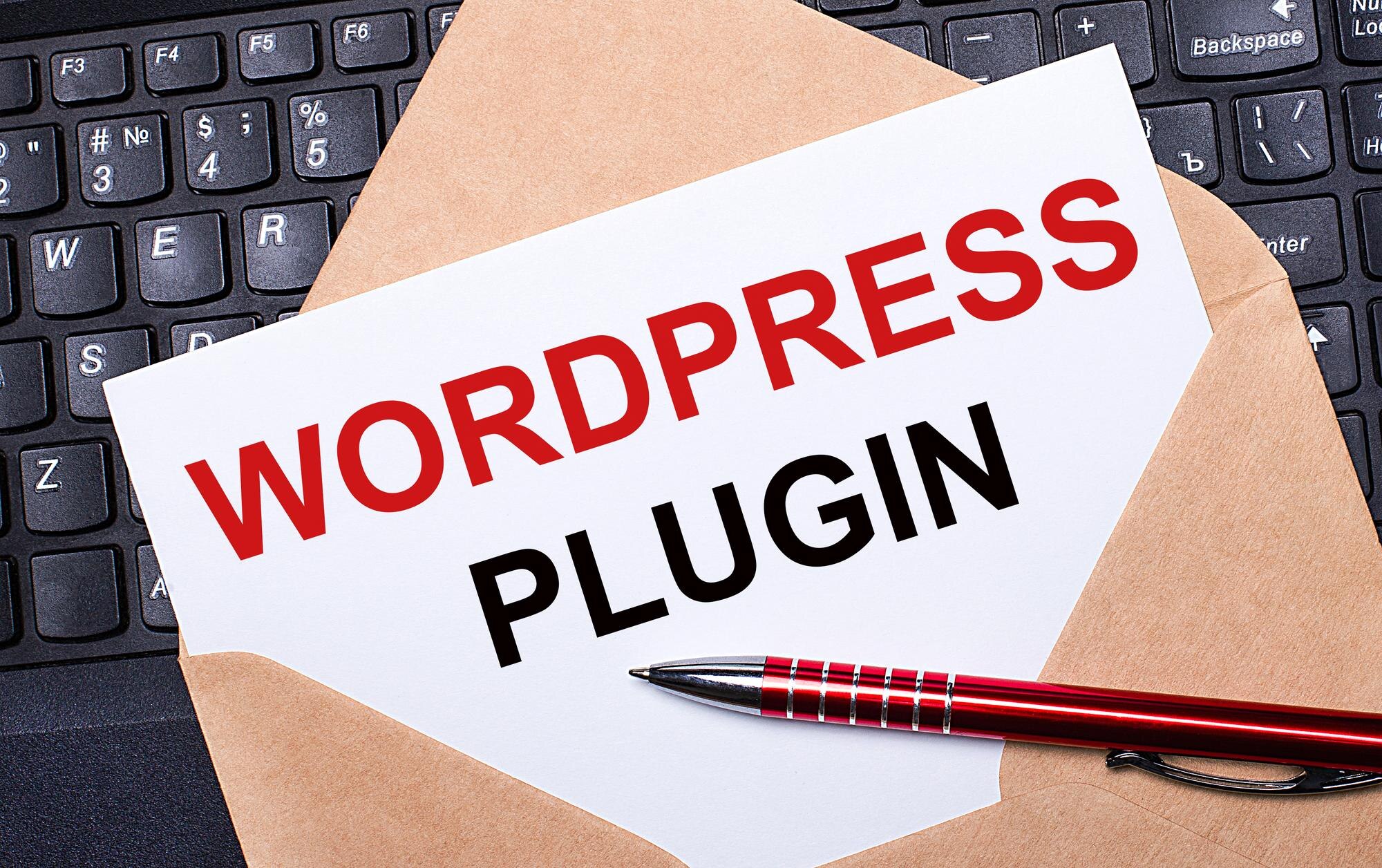 Biała kartka z napisem WORDPRESS PLUGIN w rzemieślniczej kopercie na biurku z nowoczesną klawiaturą laptopa i bordowym długopisem Płaski układ miejsca pracy